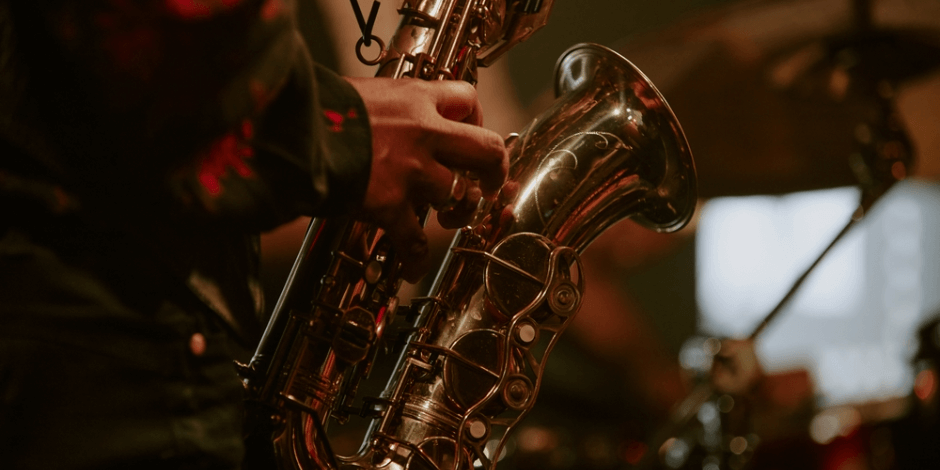 A saxophonist performs under warm stage lighting at the Bohemia Wine & Jazz Festival at Bohemia Manor Farm.