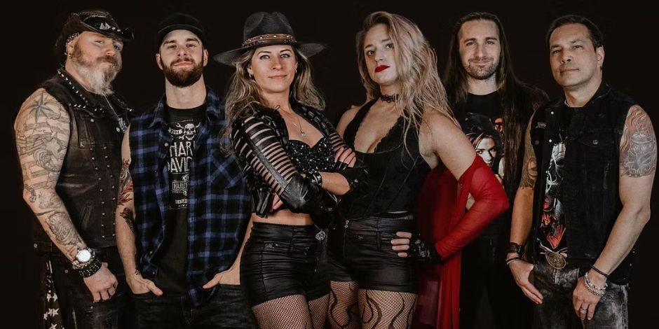 A six-member rock band in edgy black and red performance attire posing against a dark background for a promotional photo.