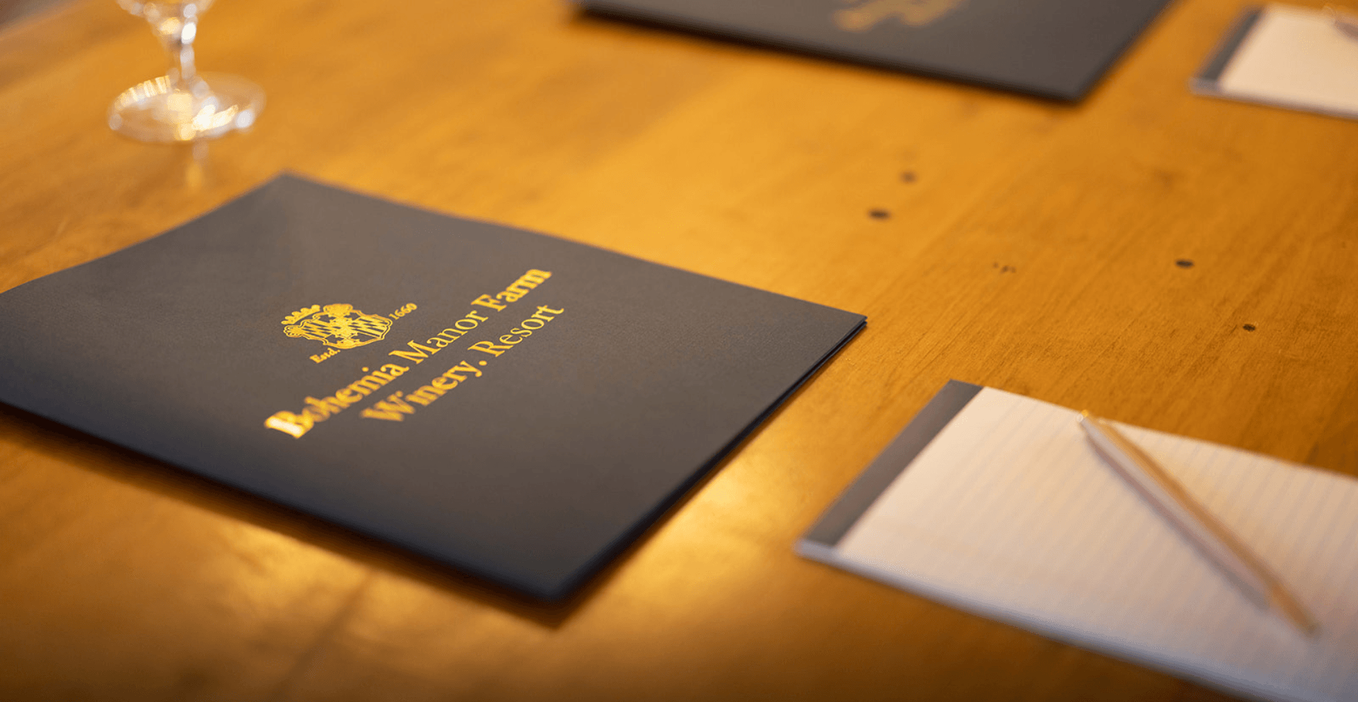 A corporate meeting table at Bohemia Manor Farm set with branded navy folders, notepads, and pens at each place